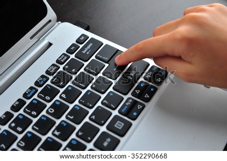 Woman hand touching laptop computer keyboard - Focus on the keyboard
