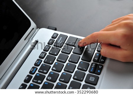 Woman hand touching laptop computer keyboard - Focus on the keyboard