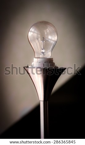 Light bulb on reflective, metallic stand, with soft backround Bulb is switched off.
