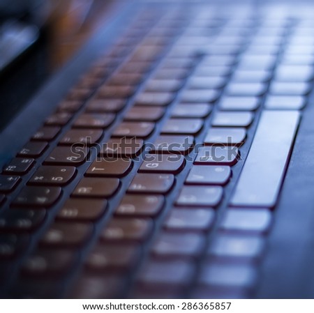 Notebook keyboard. Selective focus, focusing on keys in the center. Blueish tint. Keyboard is  german-styled (Z key in the upper row).