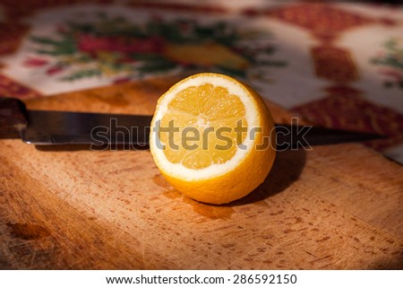 Tasty, yellow lemon on wooden cutting board. Knife on backplane. Focus on leemon pulp.