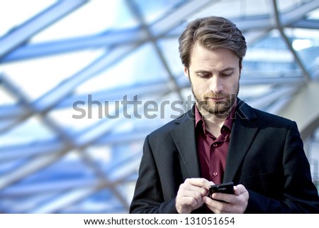 Forty Years Old Businessman Standing Inside Modern Office Building Looking On A Mobile Phone