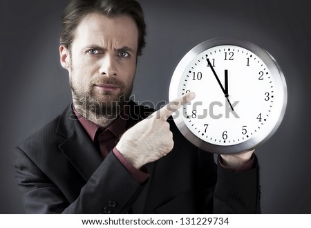 Forty years old strict demanding boss with a pointing finger on a clock - indicates a deadline hour