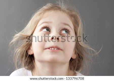 Close up portrait of happy smiling caucasian five years old blond child girl on a grey background