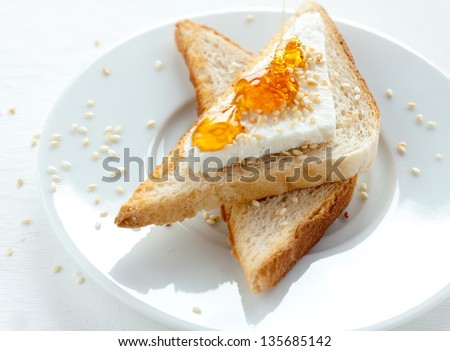Toast with cottage cheese, sesame and honey on white plate - healthy breakfast composition