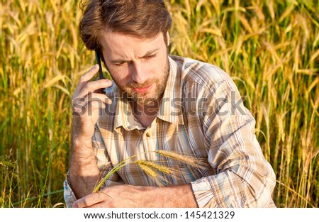 Forty years old farmer control his wheat cultivation field while talking on a mobile phone