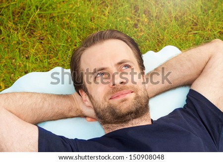 Happy smiling forty years old caucasian man laying on grass and looking up at the sky