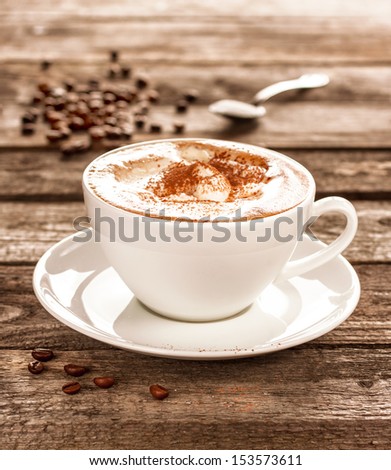 Coffee cup and beans on an old vintage planked wood table - moody still life