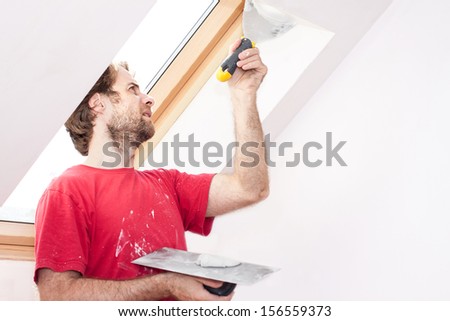 Forty years old good looking caucasian manual worker with wall plastering tools inside a house
