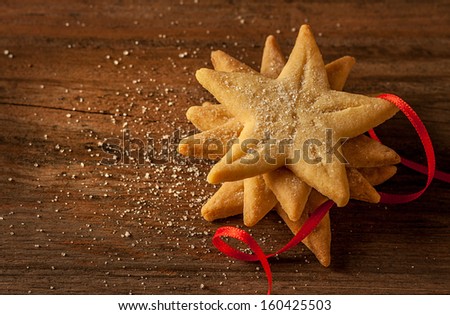 Star shaped christmas cookies and red ribbon on vintage wood background - dark moody image.