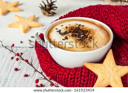 Winter cappuccino coffee in a white cup with star shaped christmas cookies and warm scarf - red and white rural still life
