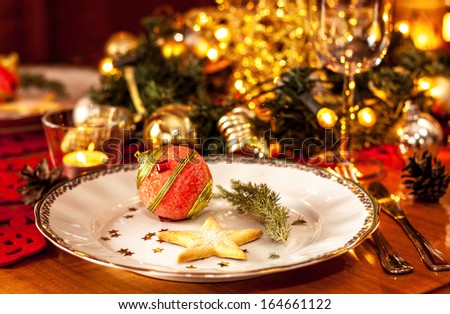 Christmas eve dinner party table setting with lights and gold glittering decorations - elegant white plate close up