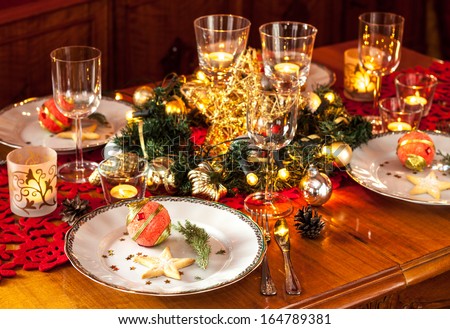 Christmas eve dinner party table setting with lights, gold glittering decorations and elegant white plates