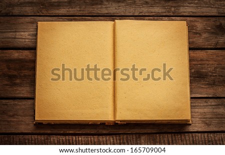 Old blank open book on vintage planked wood table from above - rustic background with text space