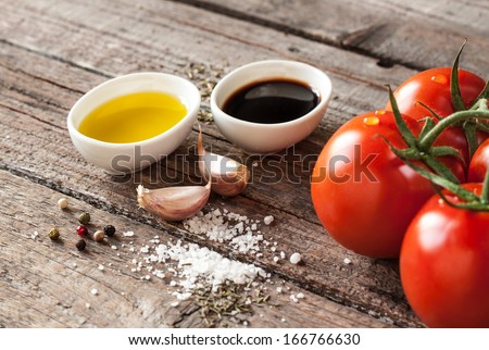 Vinaigrette or french dressing recipe ingredients on vintage wood background. Olive oil, balsamic vinegar, garlic, salt and pepper.