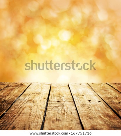 Autumn rustic template background with text space. Old vintage planked wood table in perspective on warm orange abstract bokeh - outdoor in the garden.