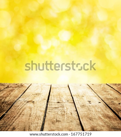 Summer rustic template background with text space. Old vintage planked wood table in perspective on bright yellow bokeh - outdoor in the garden during sunny day.