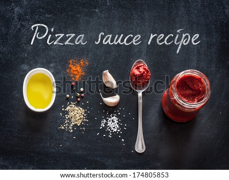 Pizza topping sauce ingredients or recipe on black background. Tomato puree, olive oil, garlic, oregano, salt and pepper from above - cooking food.