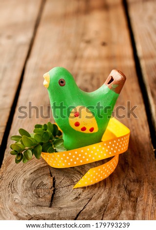 Rustic easter decoration - green bird with buxus and yellow ribbon on an old vintage planked wood table. Background with free text space.