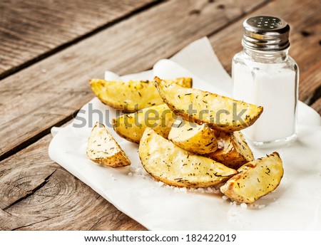 Potato wedges and salt shaker on rustic vintage planked wood table - snack bar or pub menu