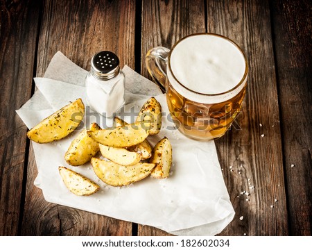 Beer mug and potato wedges on rustic vintage planked wood table - snack bar or pub menu