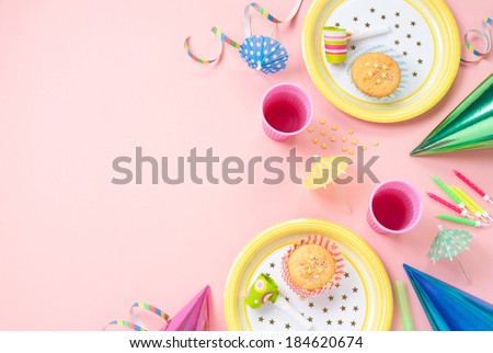 Girl birthday decorations. Pink table setting from above with muffins, drinks and party gadgets. Background layout with free text space.