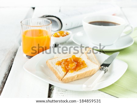 Continental breakfast - coffee, orange juice and toast on white wood table.