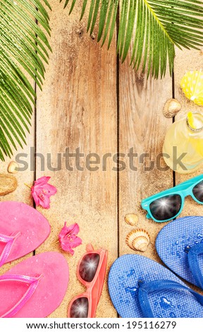 Summer holiday (vacation) tropical beach background layout with free text space. Palm tree leaves, sand, exotic flowers, sunglasses and flip flops on vintage wood - poster design.