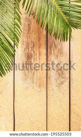 Palm tree leaves and sand on vintage planked wood. Summer holiday (vacation) tropical beach background layout with free text space.