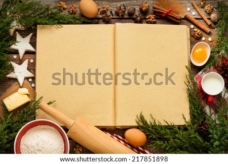 Christmas - baking cake background. Blank opened cook book with food ingredients and decorations around on vintage planked wood table from above. Layout with free text space.
