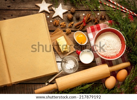 Christmas - baking cake background. Blank opened cook book with food ingredients and decorations around on vintage planked wood table from above. Layout with free text space.