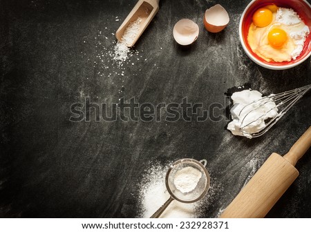 Baking cake ingredients. Bowl, flour, eggs, egg whites foam, eggbeater, rolling pin and eggshells on black chalkboard from above. Cooking course poster background - layout with free text space.
