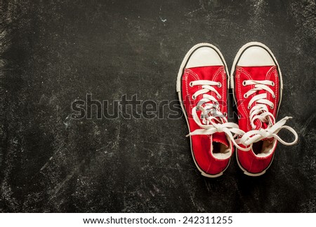Red sneakers on black chalkboard from above. Background layout with free text space.