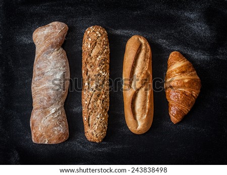 Different kinds of bread rolls on black chalkboard from above. Kitchen or bakery poster design.