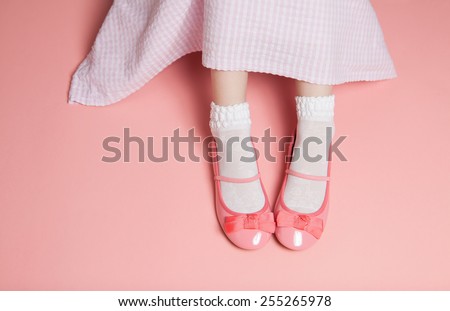 Young girl pastel pink outfit from above. Skirt and legs in white socks and flats shoes. Background layout with free text space.