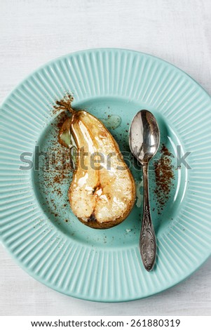 Caramelized pear with cinnamon and vintage spoon on pastel blue plate from above.