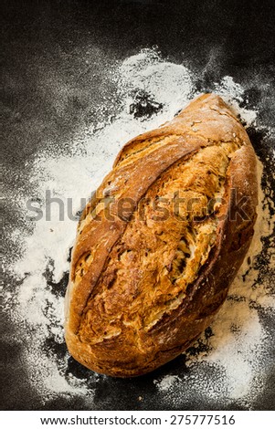 Rustic loaf of bread and flour on black chalkboard from above. Background layout with free text space.