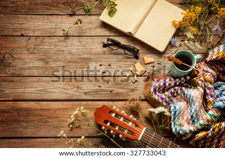 Late summer or autumn relaxation, rustic background on wood from above. Country lifestyle, rural vacation or agrotourism concept. Layout with free text space. Book, blanket, coffee and guitar.