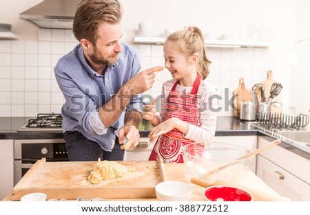 Smiling caucasian father and daughter having fun while preparing cookie dough in the kitchen. Baking - happy family time.