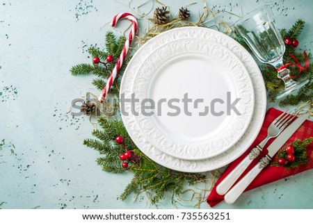 Elegant christmas table setting design captured from above (top view, flat lay). Empty white plate, glass, cutlery, candy cane and decorations. Background layout with free text (copy) space.