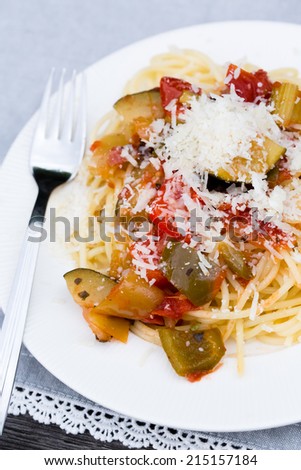 Spaghetti with vegetables and parmesan on a laced table mat and vintage table