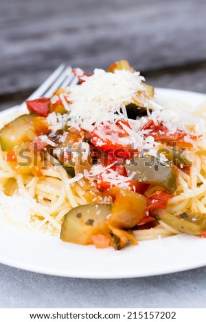 Spaghetti with vegetables and parmesan on a laced table mat and vintage table