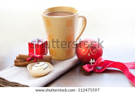 Christmas morning and new year. Cup of hot chocolate with cinnamon sticks, candy, Christmas ball and small box present on wooden table