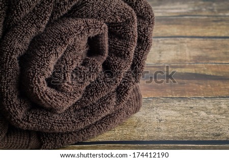 Rolled, organic cotton towel on a dark wood background.