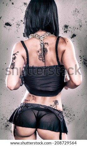 Sexy Grunge Tattoo Girl. Beautiful and erotic lady with tattoo. Studio shoot. Rear View.