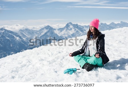Beautiful young woman doing yoga in the snow mountains. Winter Scenic in the French Alps, Les 2 Alpes