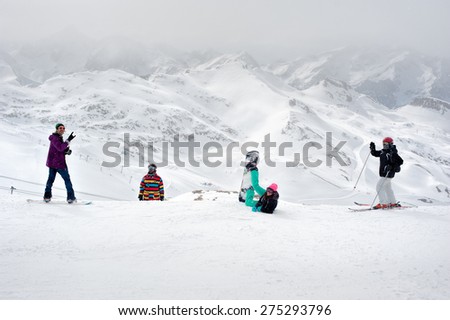Happy snowboarders and skiers enjoy on top of mountain. Happy four sportsmen with snowboard and skis standing on top of mountain