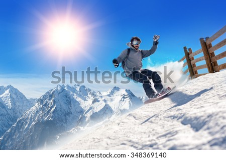 Snowboarder freerider. Snowboarder man holding snowboard in the air jumping with mountains on background
