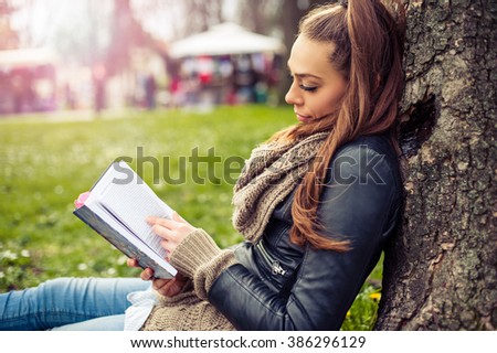 Young woman reading book. Closeup of a beautiful young woman reading book at park