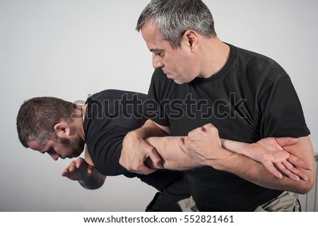 Kapap instructor demonstrates arm bar techniques with his student